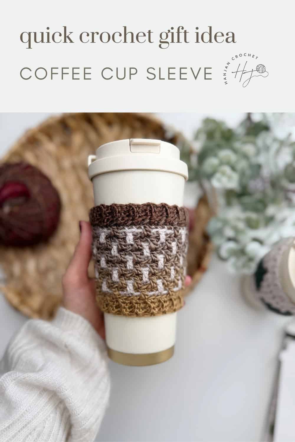 A hand holds a reusable coffee cup with a brown and white Crochet Coffee Sleeve Pattern; basket with yarn and crochet hook in the background. Text reads: "quick crochet gift idea COFFEE CUP SLEEVE.
