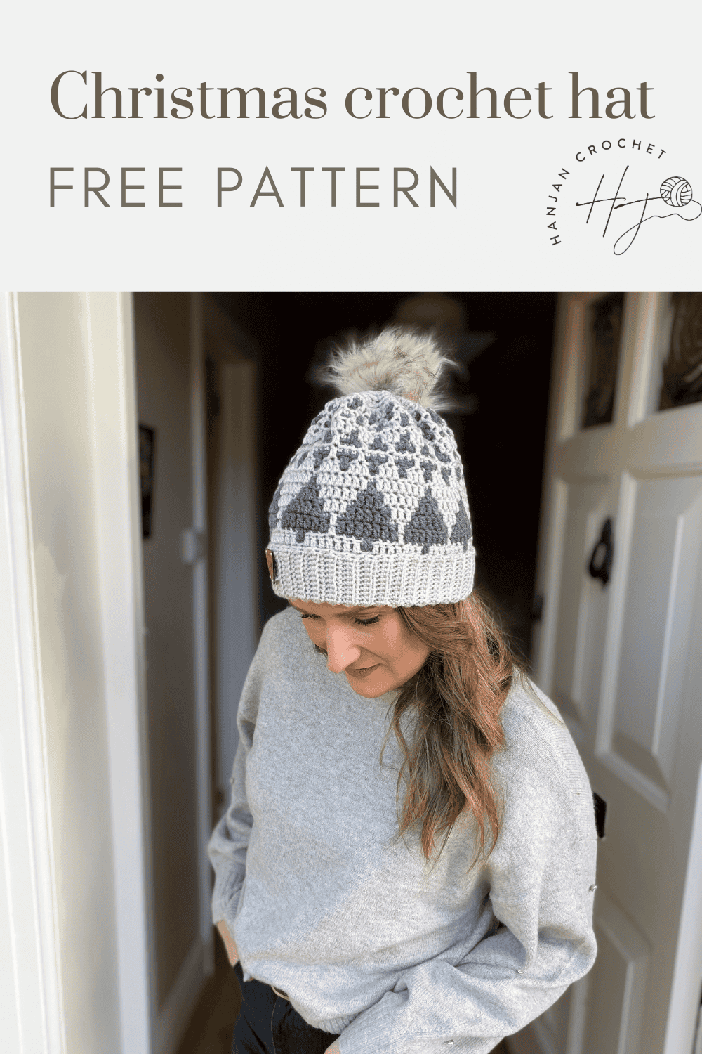 Woman wearing a gray and white crochet hat with a pom-pom stands indoors; text above reads "Christmas tree crochet hat pattern FREE PATTERN" with a crochet logo.