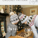 Two children wearing festive sweaters and handmade Christmas tree crochet hats, crafted from a delightful christmas tree crochet hat pattern, play chess on a small table in a cozy, holiday-decorated living room.