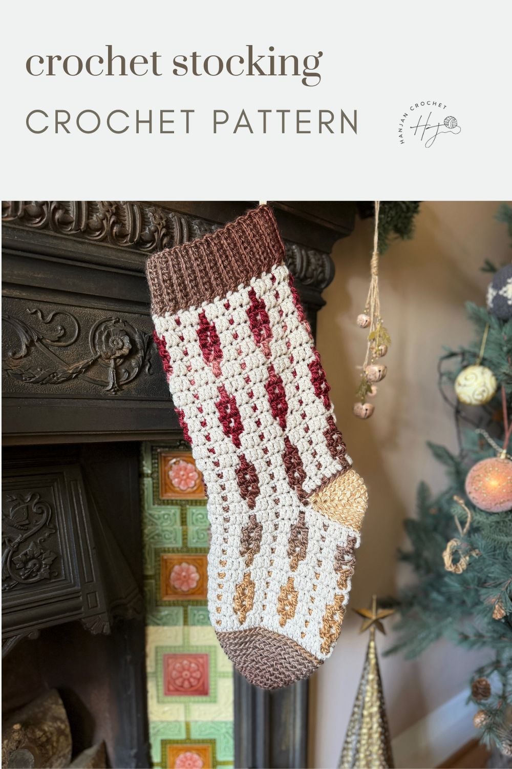 A crocheted Christmas stocking with a red, white, and brown pattern—perfect inspiration if you want to learn how to crochet a Christmas stocking—hangs from a fireplace mantle near a decorated Christmas tree.