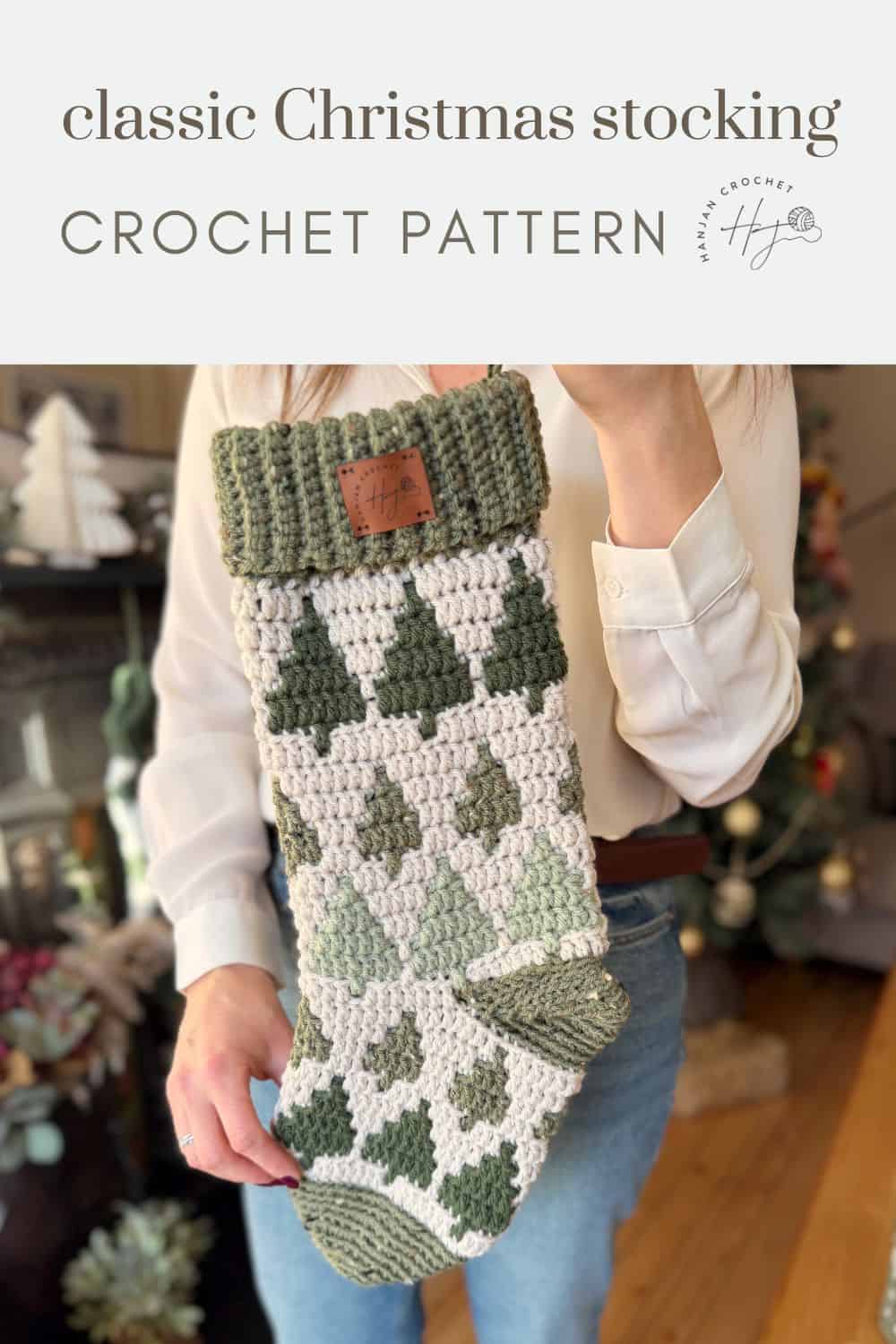 A person holds a crocheted Christmas stocking with green trees and a ribbed green cuff, beautifully displaying a classic crochet stocking pattern.