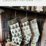 Three green and white mosaic crochet stockings, made from a festive crochet stocking pattern, hang from a fireplace mantel adorned with Christmas ornaments and greenery.