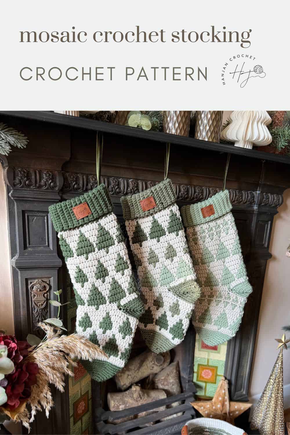 Three green and white mosaic crochet stockings, made from a festive crochet stocking pattern, hang from a fireplace mantel adorned with Christmas ornaments and greenery.