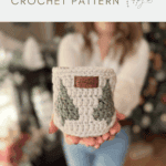 A person holds a small christmas crochet basket with a tree pattern and leather tag, in front of a blurred background with festive decor. Text reads "small crochet basket CROCHET PATTERN.