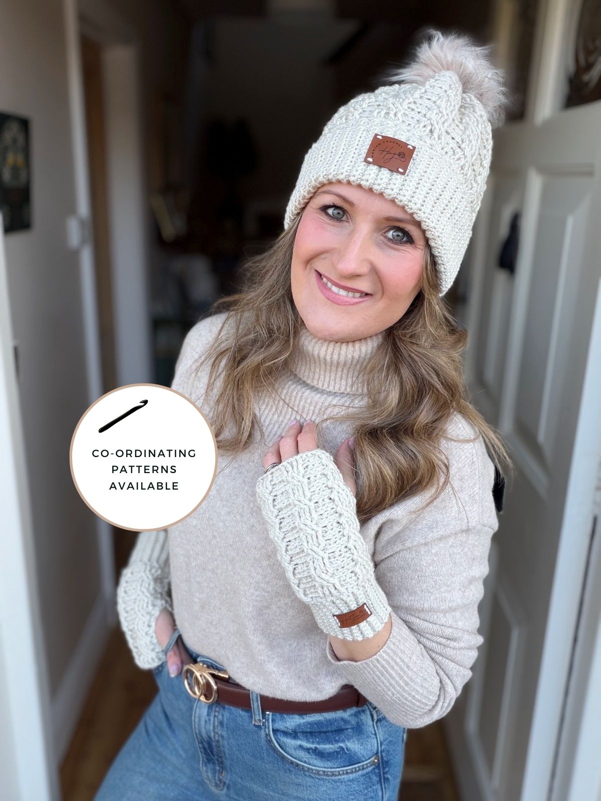 Woman wearing a cream crochet hat and matching fingerless gloves, standing indoors and smiling at the camera. Text overlay reads: "Co-ordinating patterns available, including a crochet wrist warmers free pattern.