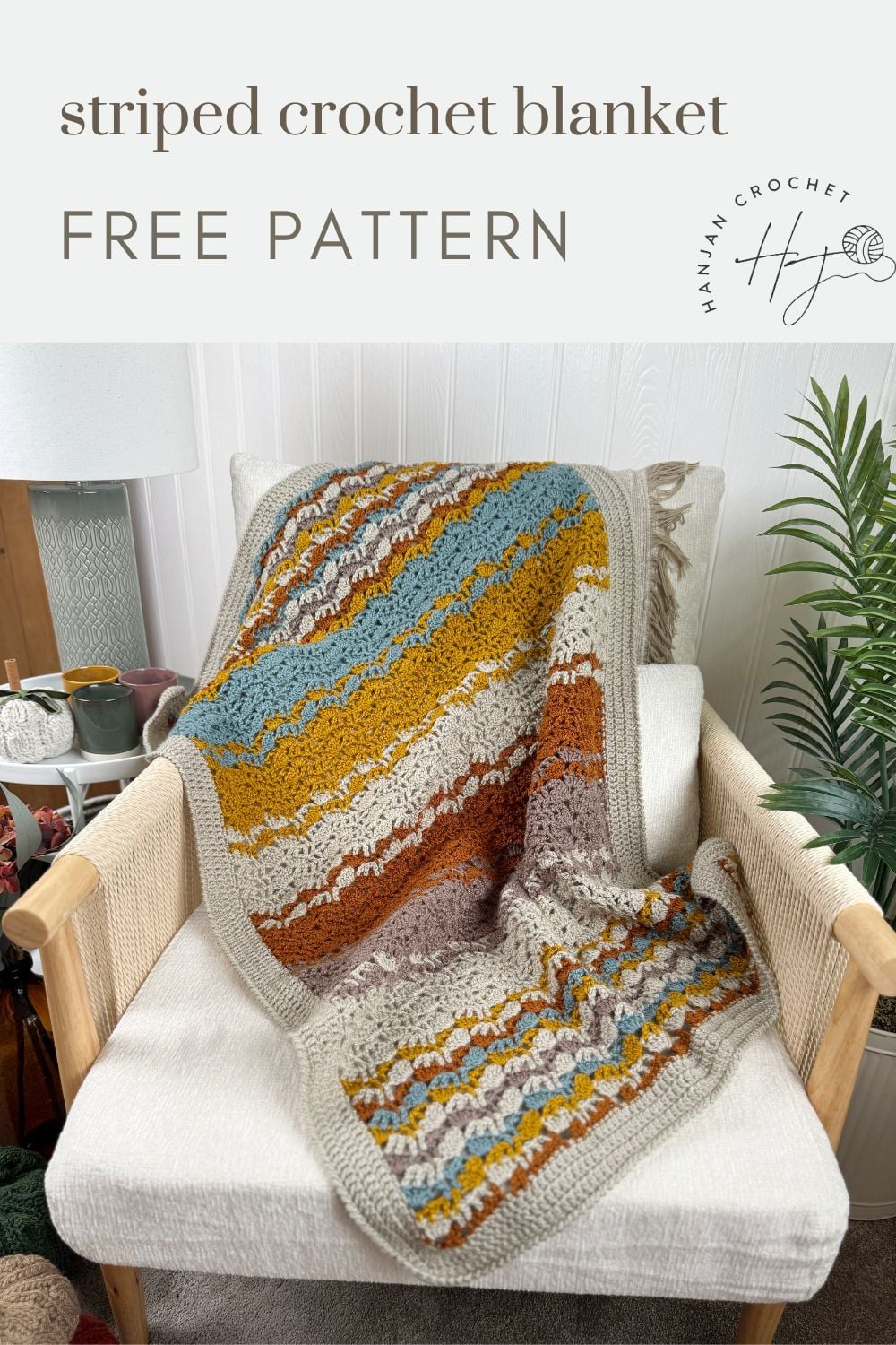 A striped crochet blanket in earthy tones and blue, featuring a lacy crochet blanket pattern, draped over a beige armchair with text offering a free pattern.