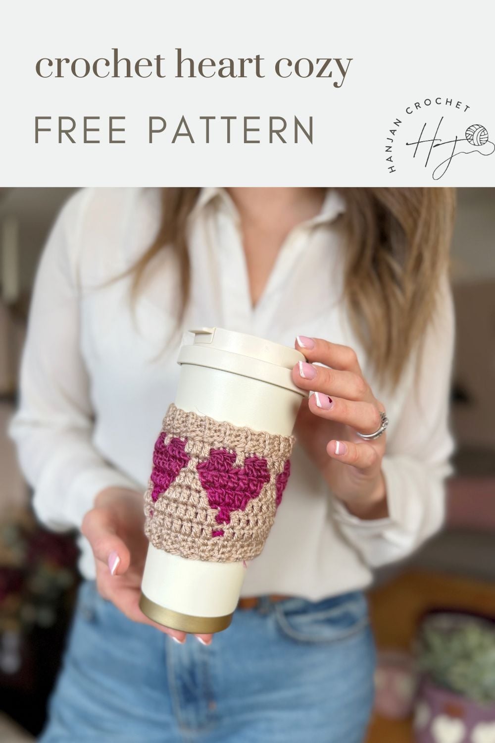 A person holds a white travel mug wrapped with a beige and pink crochet coffee cozy with heart; text above reads, "crochet heart cozy FREE PATTERN.