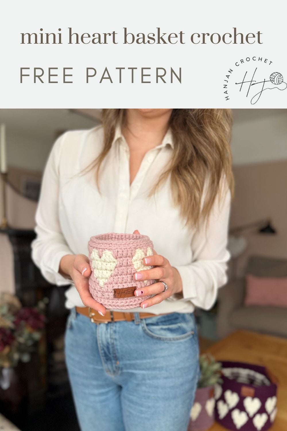 A woman in a white shirt and blue jeans holds a pink basket with heart patterns; text above reads "mini heart basket crochet free pattern"—perfect for anyone looking for a cute crochet heart basket pattern.