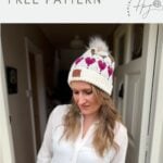 A woman in a white blouse and a crochet beanie with pink heart patterns stands indoors under a banner that reads "Valentines crochet pattern FREE PATTERN," showcasing the Free Crochet Heart Hat Pattern.