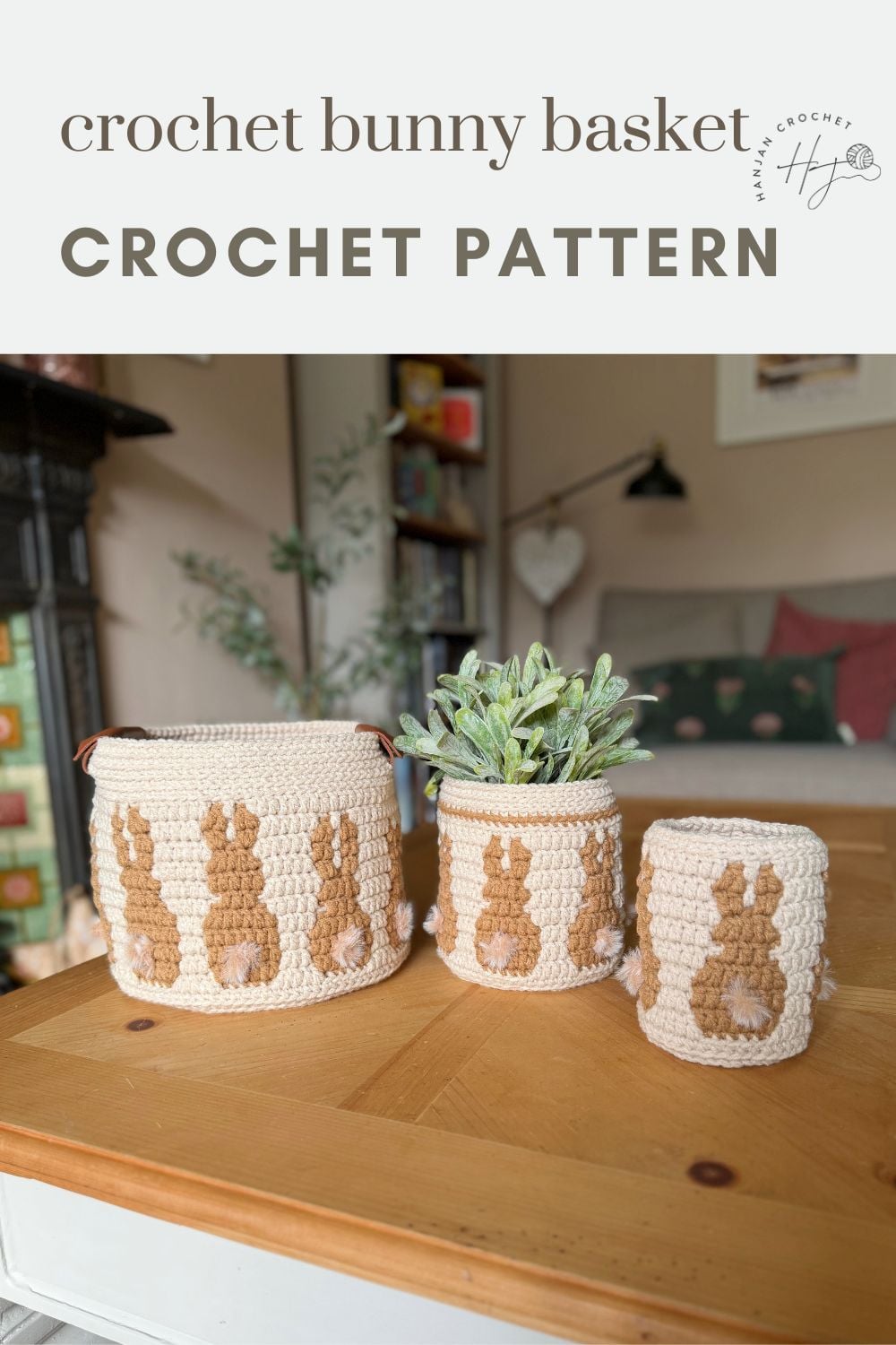 Three crochet baskets of varying sizes with brown bunny designs are displayed on a wooden table, plant in the middle. Text above reads “crochet bunny basket CROCHET PATTERN.” Perfect for those seeking a charming crochet bunny basket pattern.