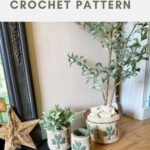 Three crocheted baskets with green clover patterns are displayed beside a potted plant and a decorative star on a wooden floor next to a fireplace.