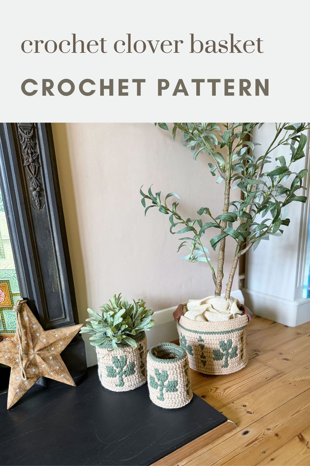 Three crocheted baskets with green clover patterns are displayed beside a potted plant and a decorative star on a wooden floor next to a fireplace.