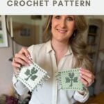 Woman holding two crochet shamrock coasters with a green clover pattern, standing indoors with plants and shelves in the background. Text reads "crochet coaster CROCHET PATTERN.