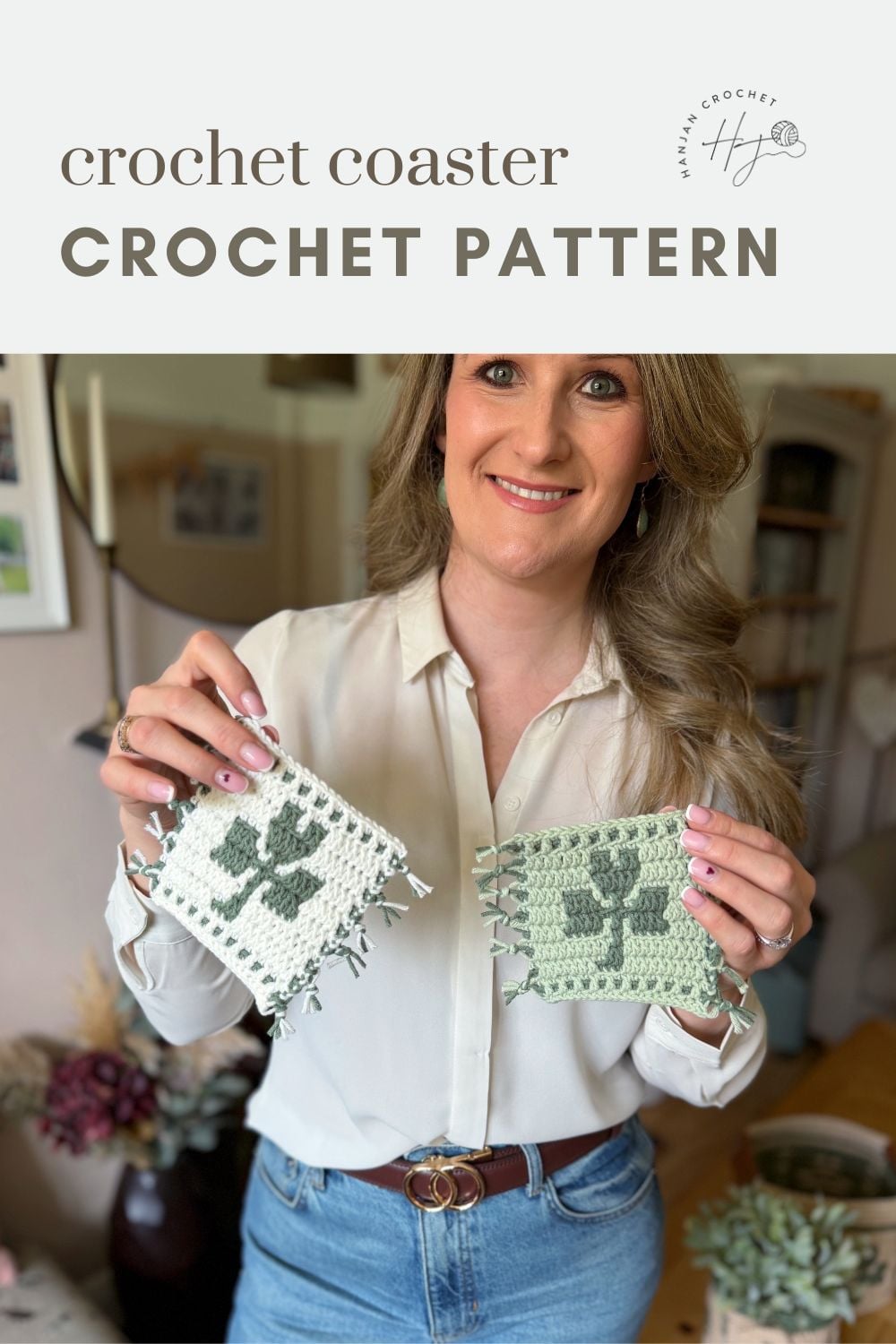 Woman holding two crochet shamrock coasters with a green clover pattern, standing indoors with plants and shelves in the background. Text reads "crochet coaster CROCHET PATTERN.