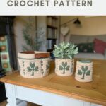 Three crochet baskets with green shamrock patterns are displayed on a wooden coffee table in a cozy living room setting.
