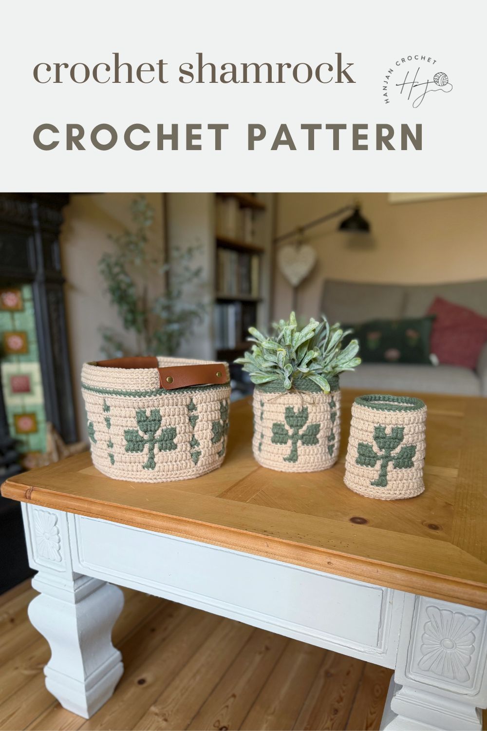 Three crochet baskets with green shamrock patterns are displayed on a wooden coffee table in a cozy living room setting.