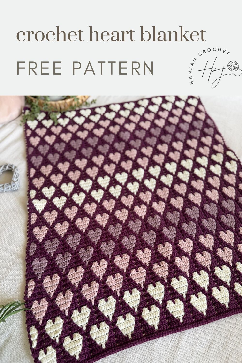 A crochet blanket with a repeating heart pattern in pink and cream colors on a dark purple background, displayed flat. Text reads "crochet heart blanket FREE PATTERN.