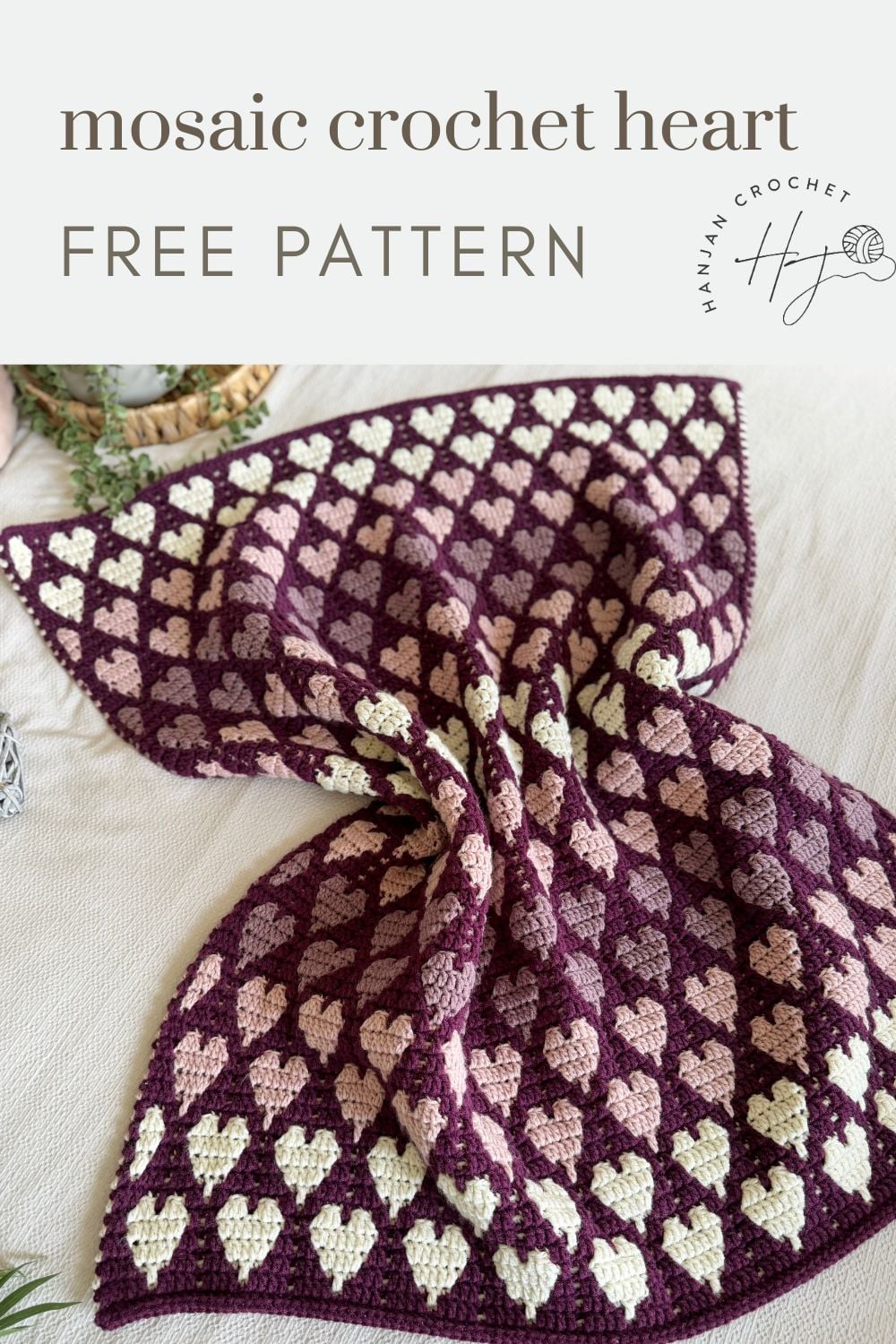 A crocheted blanket featuring a repeating heart pattern in cream and pink on a dark purple background, displayed with the text "mosaic crochet heart FREE PATTERN.