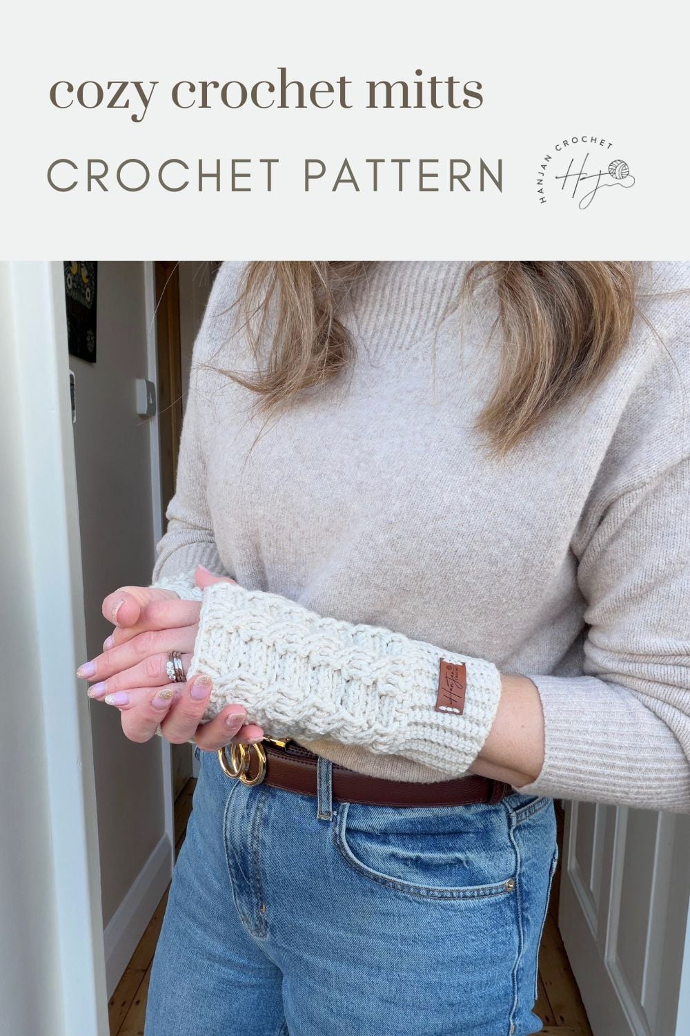 A person wearing beige crochet wrist warmers and a light sweater, holding one hand with the other. Text reads: “cozy crochet mitts CROCHET PATTERN – crochet wrist warmers free pattern.”.