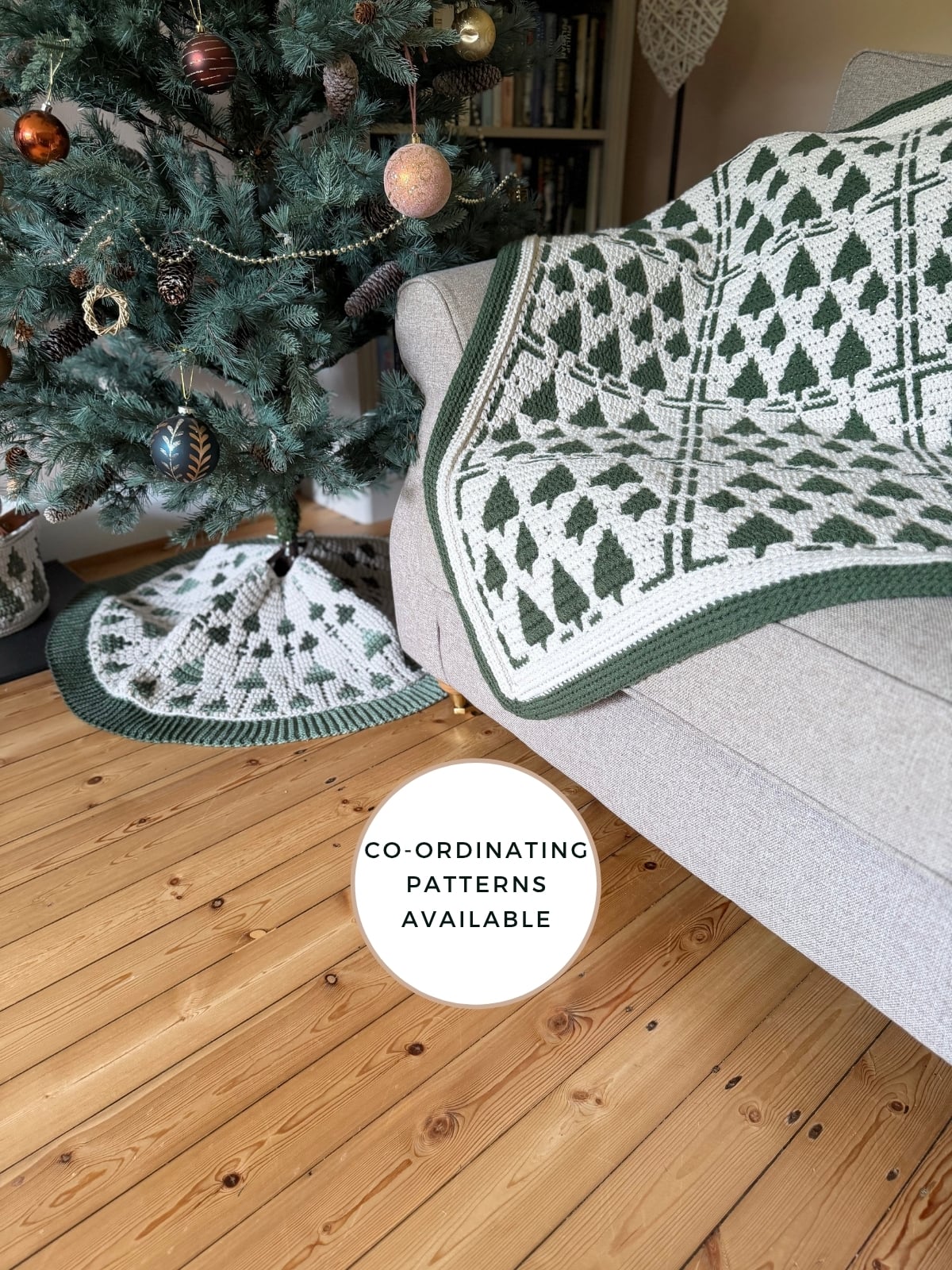 A Christmas tree with a patterned tree skirt stands next to a sofa draped with a matching Christmas crochet afghan. A sign on the floor reads "Co-ordinating patterns available.