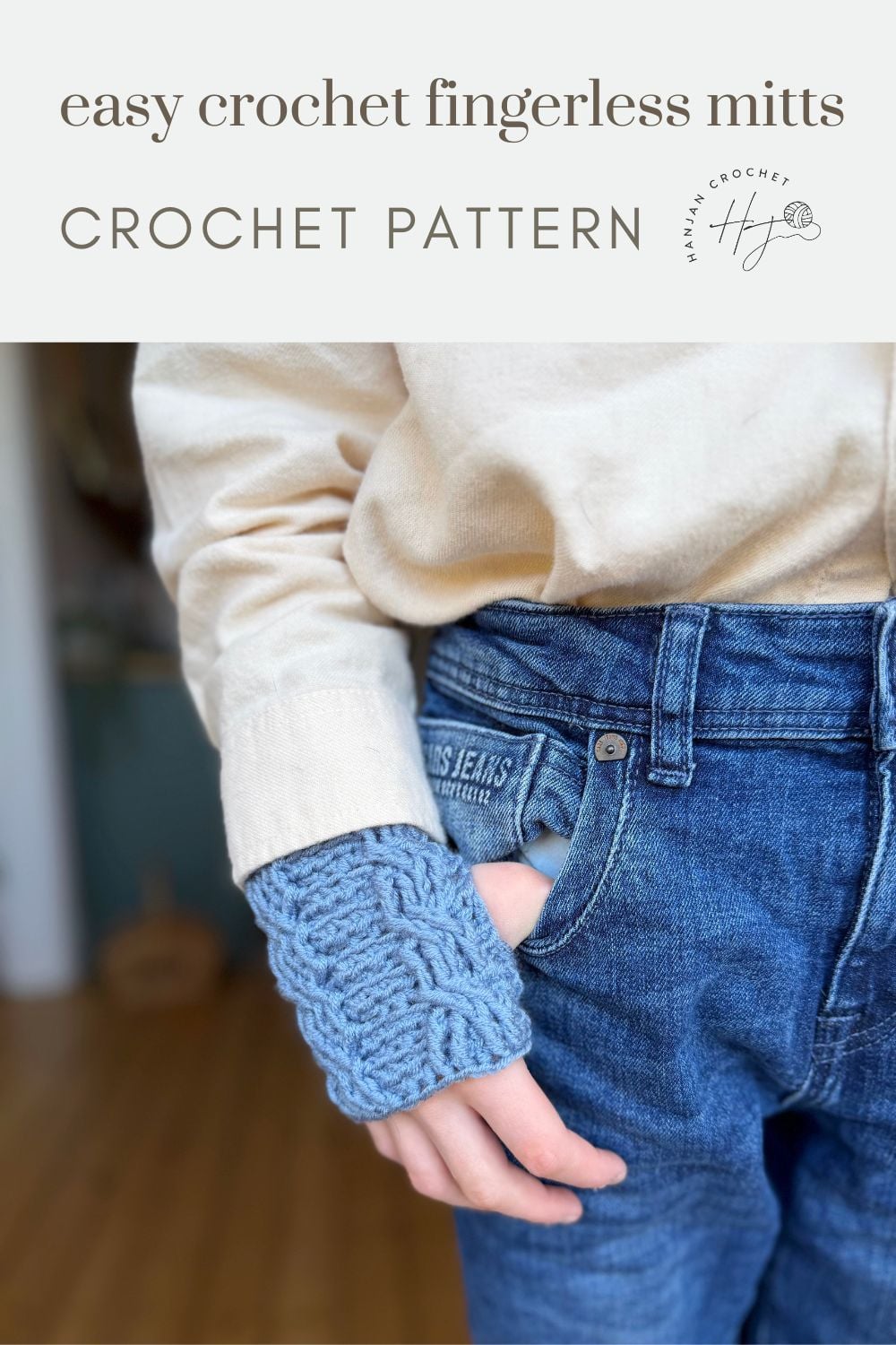 A person wearing blue crocheted fingerless mitts and jeans, with only one mitt visible. Text at the top reads "easy crochet wrist warmers free pattern CROCHET PATTERN.