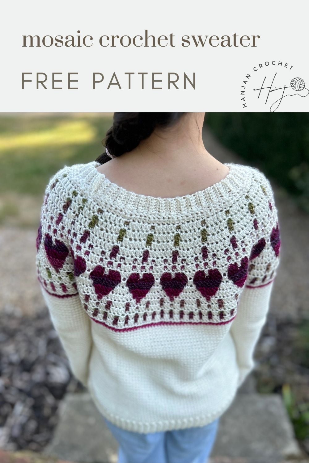 A person wears a white crochet sweater with heart and flower patterns in red and green on the yoke, viewed from behind. Text reads: “mosaic crochet sweater FREE PATTERN.”.