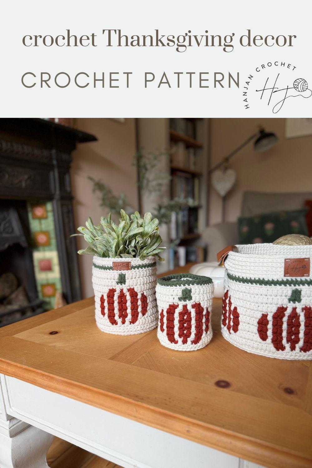 Three crocheted containers with pumpkin designs, including a charming crochet pumpkin basket, sit on a wooden table in a cozy living room.