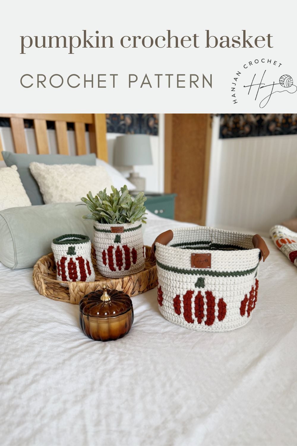 Three crochet baskets with pumpkin designs are displayed on a bed, along with a small plant and a decorative crochet pumpkin basket jar on a woven tray.
